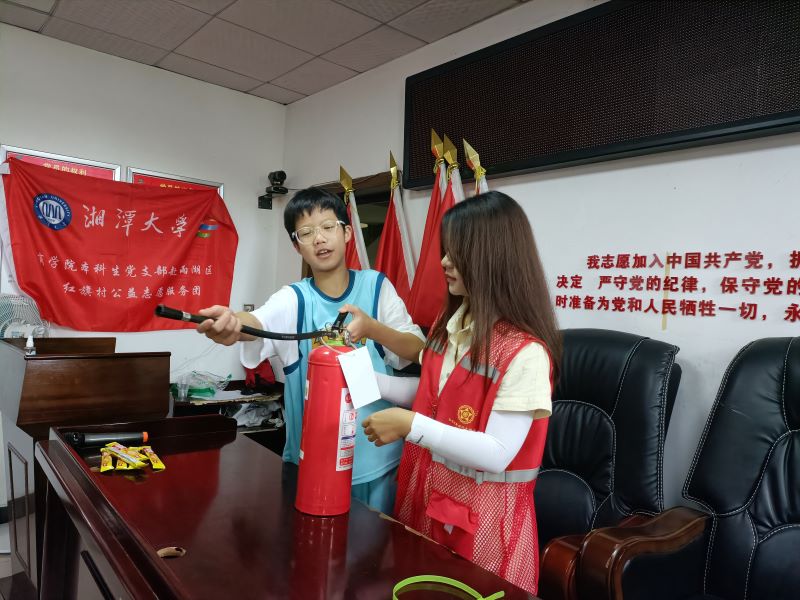 圖為志愿者向小朋友演示如何使用滅火器的場景