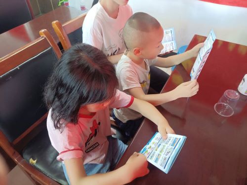 圖為小朋友閱讀防溺水安全教育知識手冊的場景