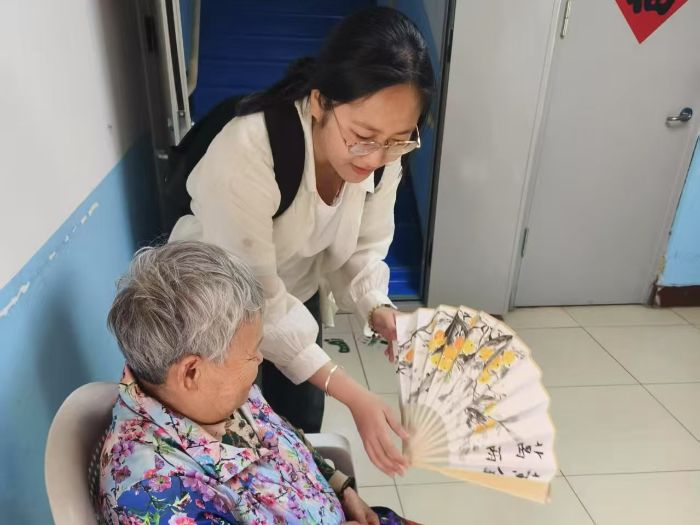 圖為實踐團成員張文萱在老年公寓為老人展示扇面繪畫